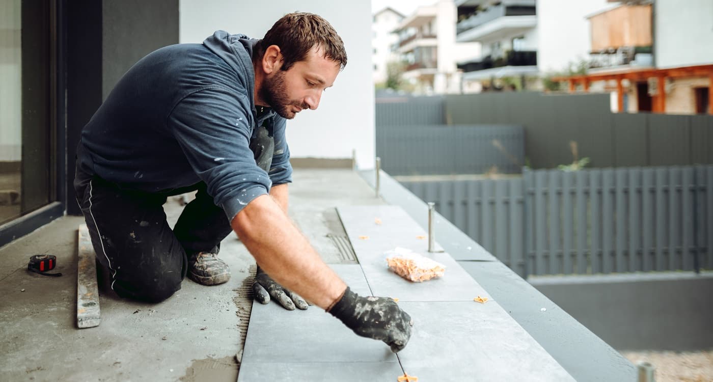 Fliesenleger beim Verlegen neuer Fliesen auf einem Balkon
